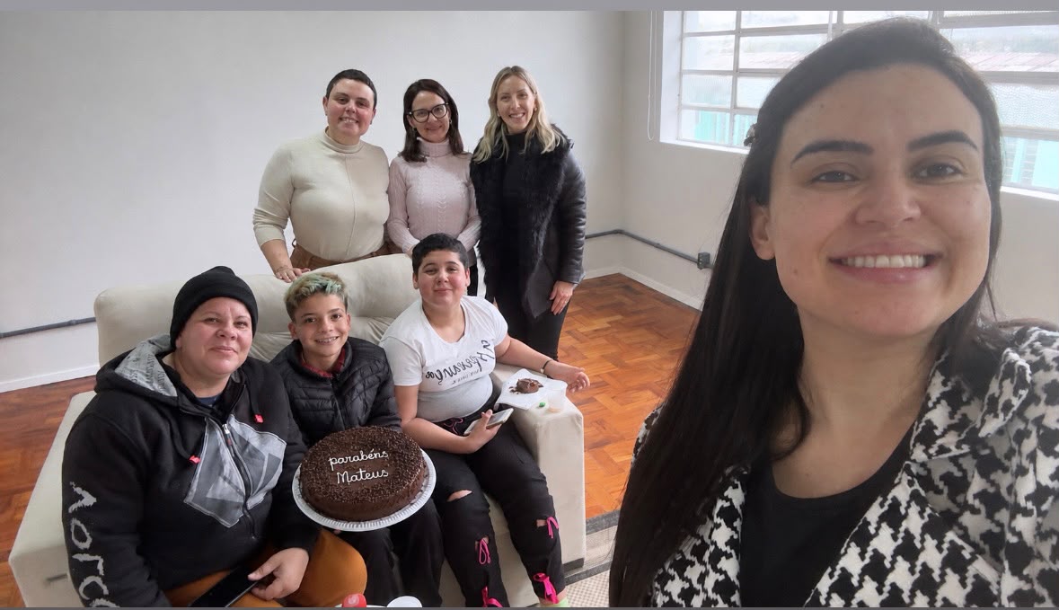 Mateus, sua irmã, participantes e equipe da FECA reunidos ao redor do bolo de aniversário